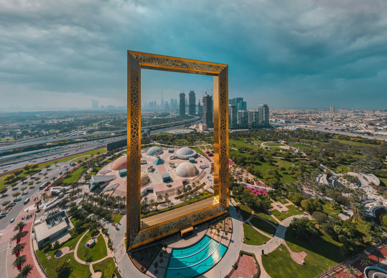 Aerial view of the Dubai Frame at Zabeel Park with the city skyline in the background on a cloudy day