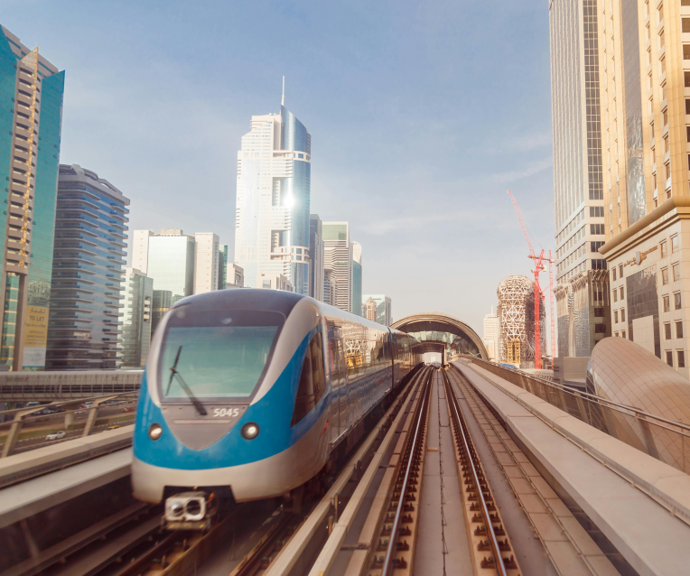 Dubai Metro train on elevated tracks along Sheikh Zayed Road with modern skyscrapers in the background.