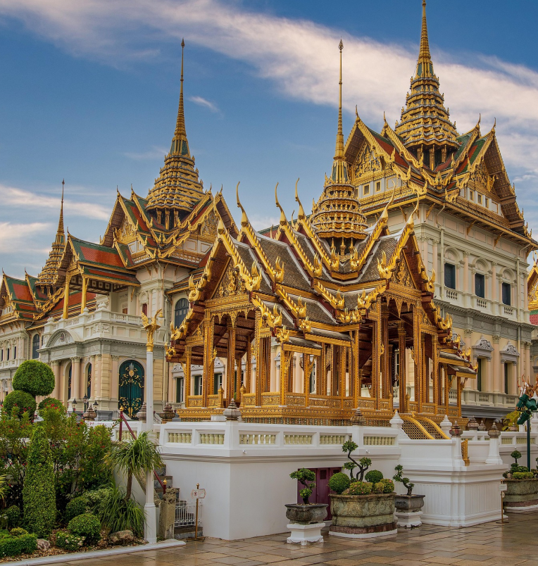 Ornate golden pavilion and traditional Thai royal architecture at the Grand Palace in Bangkok under a bright blue sky.