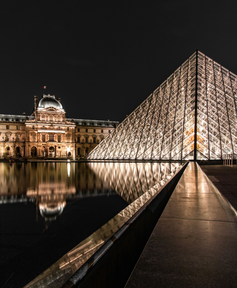 Louvre Museum glass pyramid illuminated at night in Paris, France