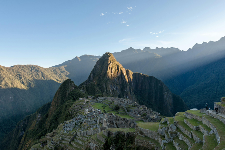 Machu Picchu Inca ruins in Peru with Huayna Picchu mountain at sunrise, terraces and valleys below.