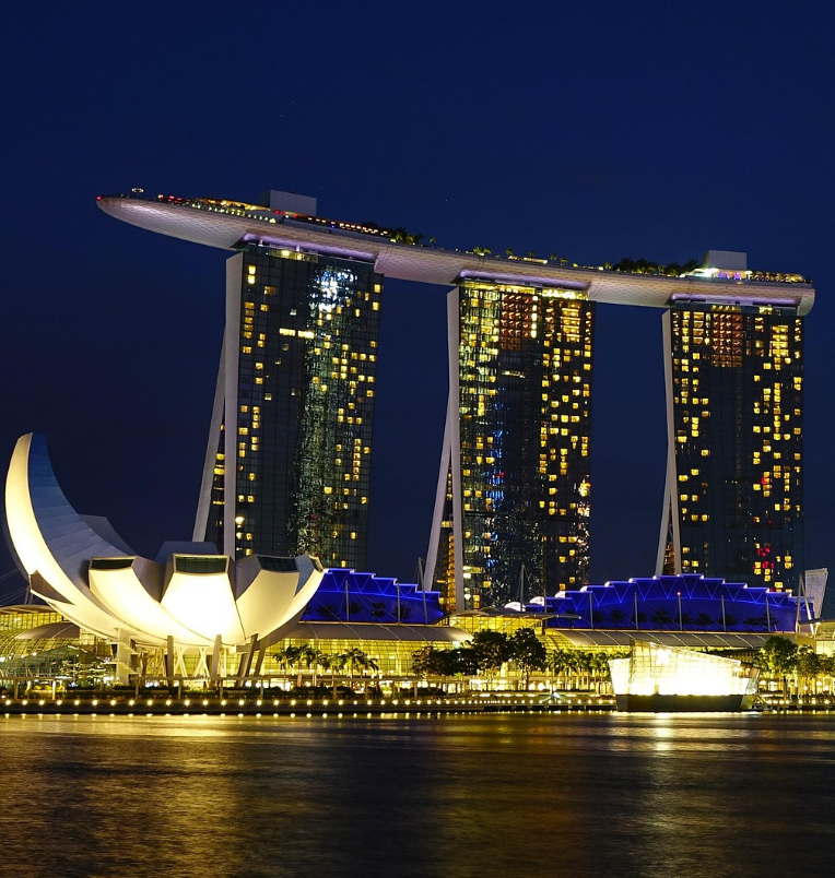Marina Bay Sands hotel and SkyPark illuminated at night in Singapore, overlooking the waterfront and city skyline.