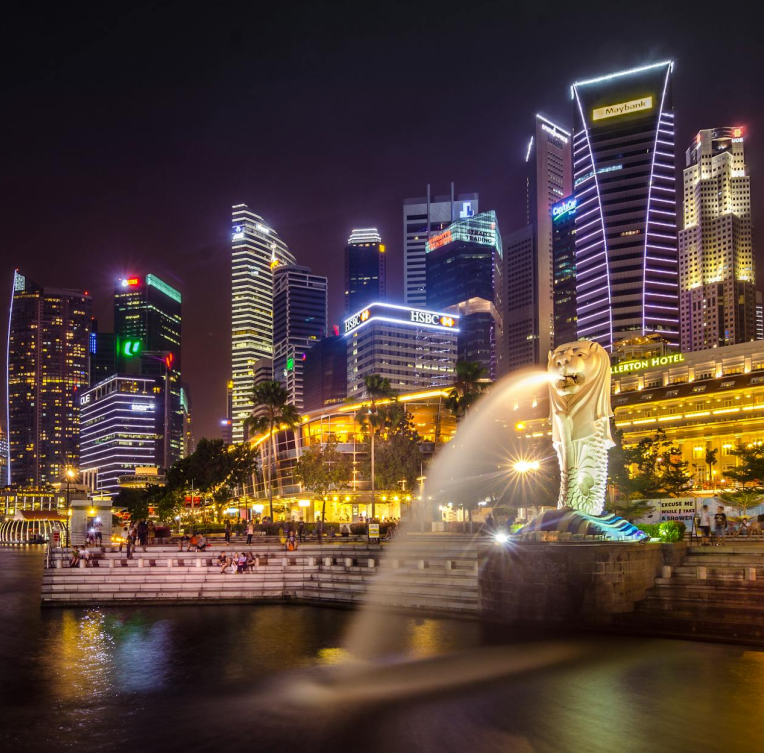 Merlion Park at Marina Bay in Singapore illuminated at night with the city skyline and skyscrapers in the background.