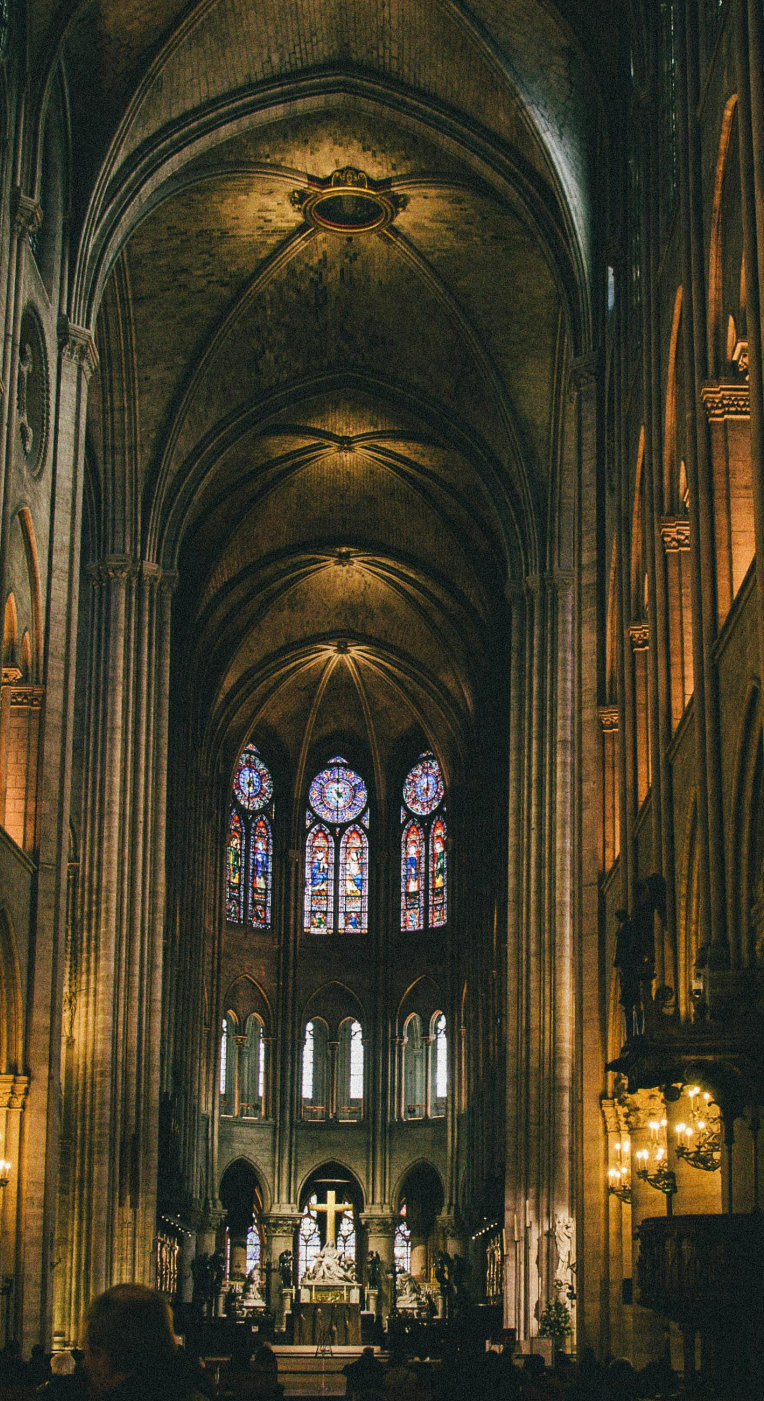 Interior of Notre-Dame Cathedral in Paris with vaulted arches and stained-glass windows.