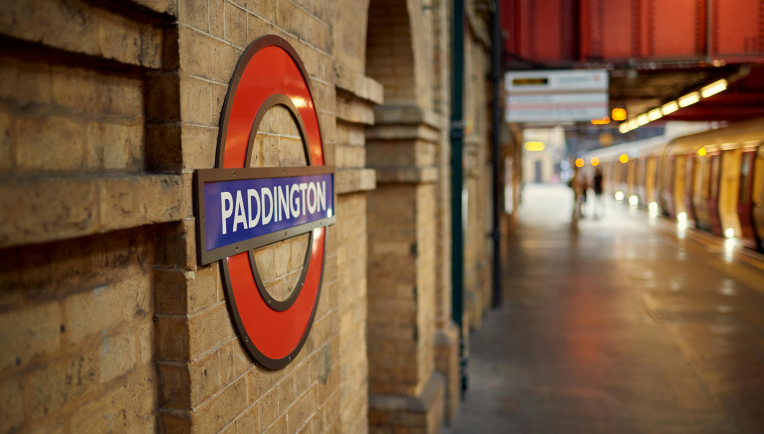 Paddington Station London Underground roundel on a brick platform with a Tube train in the background.