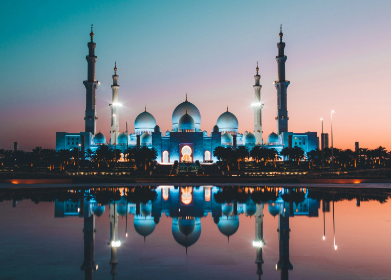 Sheikh Zayed Grand Mosque in Abu Dhabi illuminated at dusk with stunning reflections in the water, near top hotels and accommodations