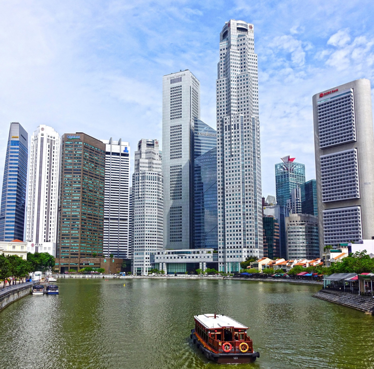 Singapore River with traditional bumboat cruising toward Boat Quay, surrounded by the modern skyscrapers of the Central Business District.