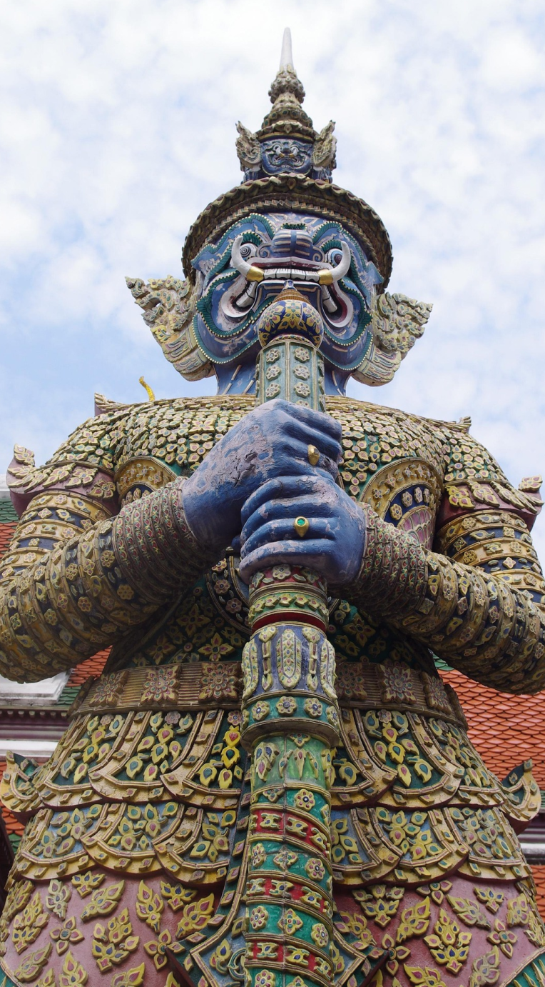 Close-up of a blue yaksha guardian statue holding a mace, decorated with intricate patterns at a Thai temple in Bangkok.
