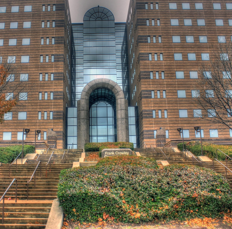 Front entrance of the Frank Crowley Courts Building in Dallas, Texas, featuring its architectural archway, steps, and landscaped surroundings.