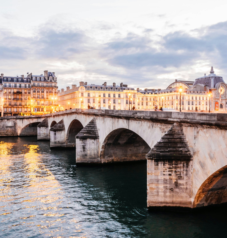 Pont Neuf bridge crossing the River Seine in Paris, France at dusk with historic buildings illuminated.