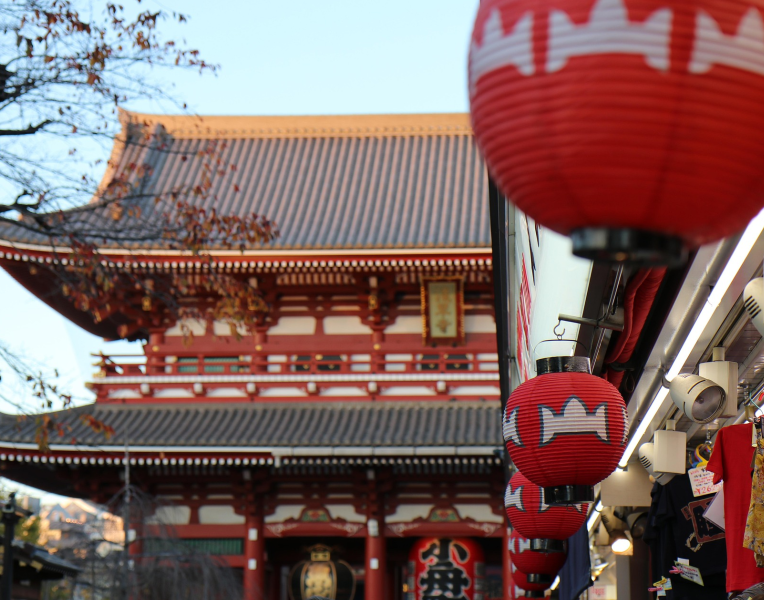 Red lanterns hanging along a street in Asakusa with Sensō-ji Temple visible in the background in Tokyo, Japan.