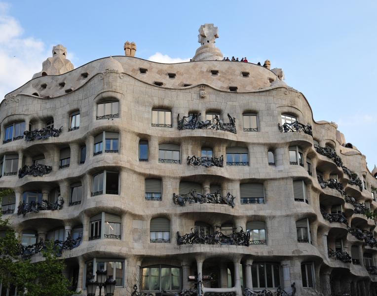 Casa Milà (La Pedrera) in Barcelona designed by Antoni Gaudí, featuring its wavy stone facade, wrought-iron balconies, and distinctive rooftop chimneys.