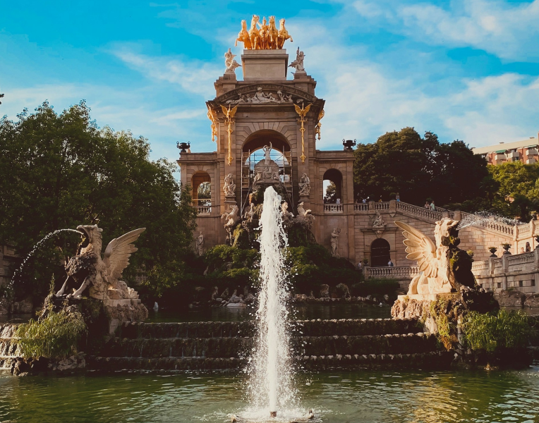 Cascada Monumental fountain in Parc de la Ciutadella, Barcelona, with golden quadriga statue, ornate arch, winged sculptures, and cascading water under a blue sky.
