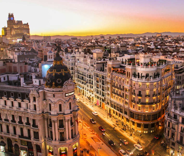Metropolis Building on Gran Vía in Madrid at sunset, showcasing the iconic dome and illuminated historic architecture overlooking the city skyline.