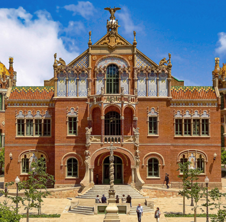 Historic modernist pavilion at Hospital de Sant Pau in Barcelona, featuring ornate brick facade, colorful ceramic tiles, and Catalan Art Nouveau architectural details.