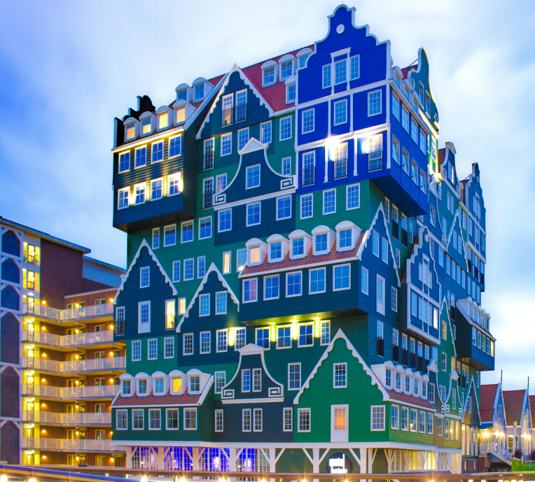 Inntel Hotel Amsterdam Zaandam with stacked traditional Dutch house facades illuminated at dusk in the Netherlands.