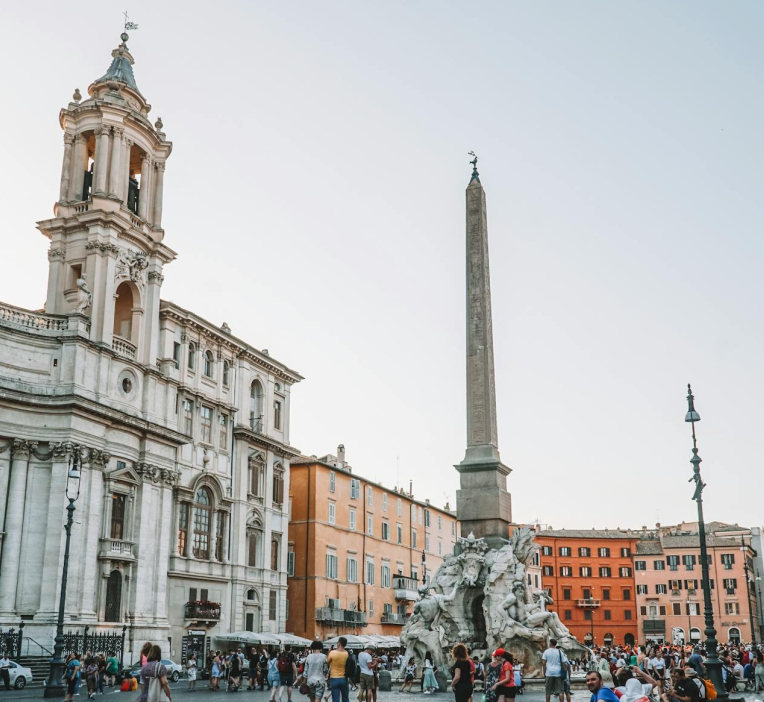 Piazza Navona in Rome with Fountain of the Four Rivers and obelisk, Sant’Agnese in Agone church and colourful historic buildings in the background.