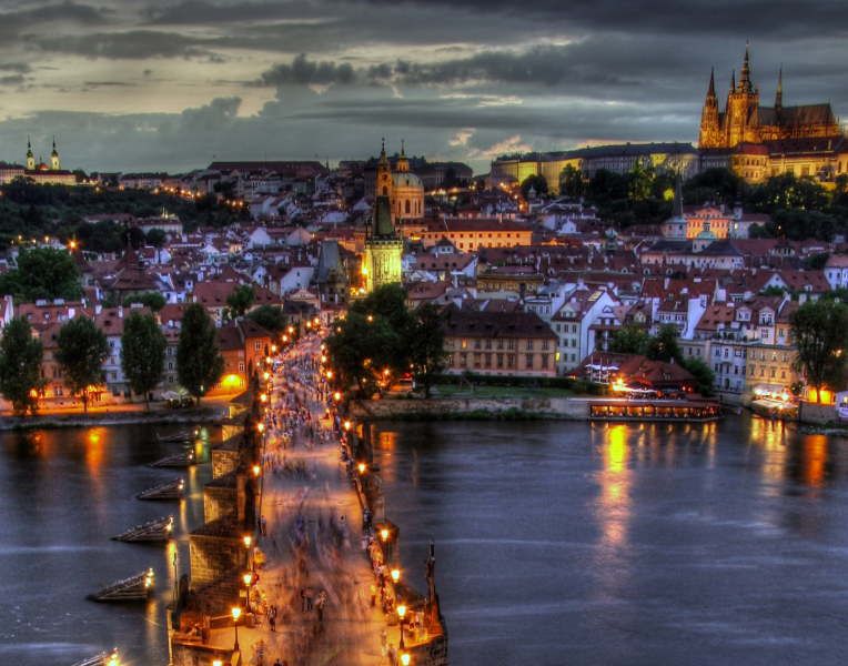 Night view of Charles Bridge in Prague crossing the Vltava River with illuminated Old Town and Prague Castle in the background, Czech Republic.