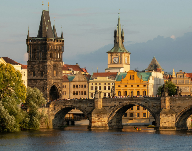 Charles Bridge in Prague with the Old Town Bridge Tower and historic city buildings along the Vltava River, Czech Republic.