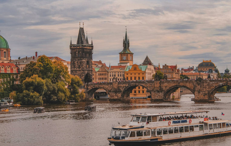 Charles Bridge in Prague spanning the Vltava River with historic towers and city skyline in the background, Czech Republic.