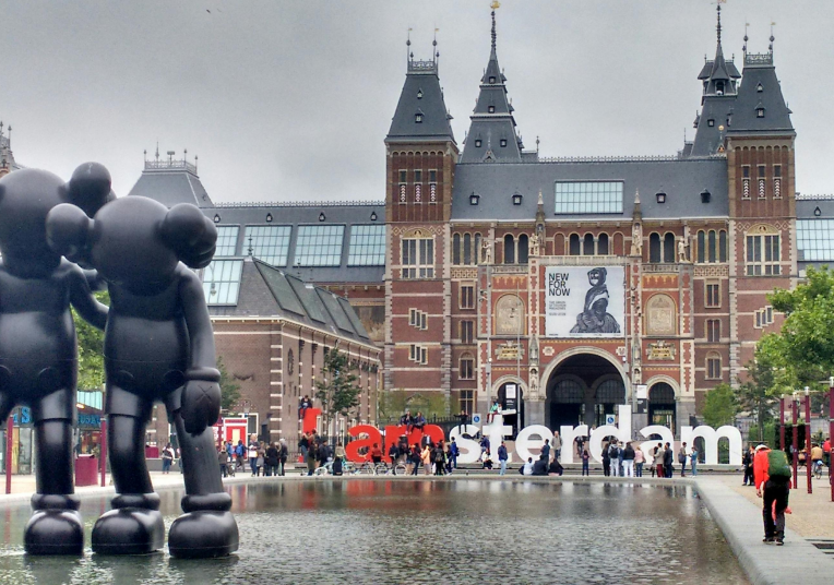 Rijksmuseum in Amsterdam with the famous I amsterdam sign and reflecting pool at Museumplein, Netherlands.