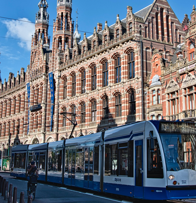 Tram passing in front of the Rijksmuseum in Amsterdam at Museumplein, showcasing the historic red-brick facade and city transport.