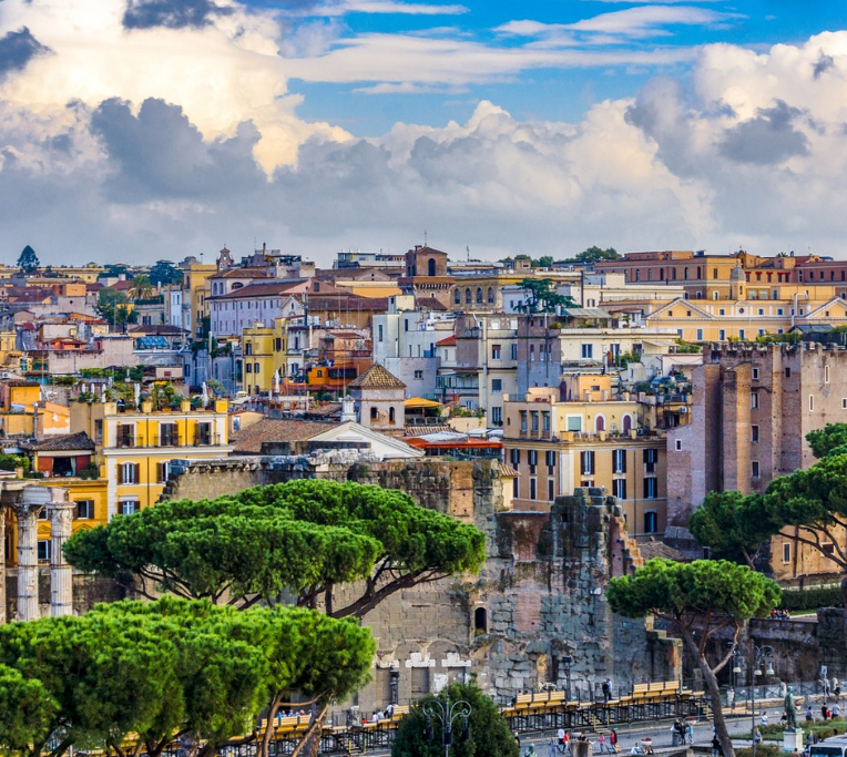 Panoramic view of Rome skyline with Palatine Hill, Roman Forum ruins and umbrella pine trees under dramatic clouds in Italy.