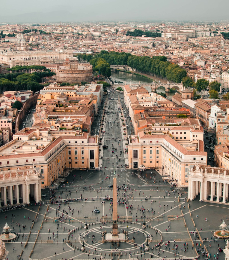 Aerial view of St Peter’s Square in Vatican City, Rome, with central obelisk, colonnades and Via della Conciliazione leading toward the Tiber River.