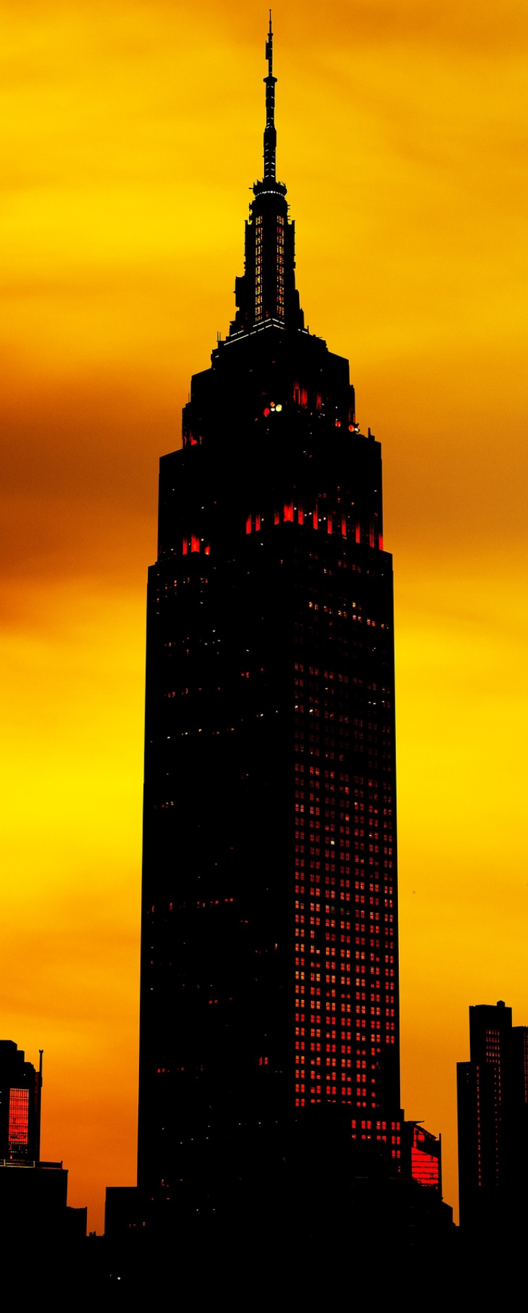 Empire State Building silhouetted against a vivid orange sunset in New York City.