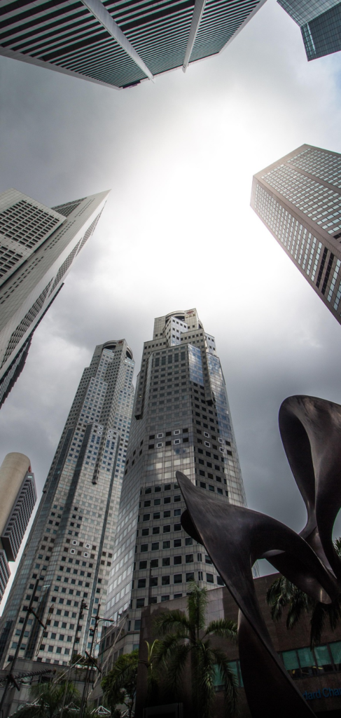 Low-angle view of Raffles Place skyscrapers and a modern public sculpture in Singapore’s Central Business District.