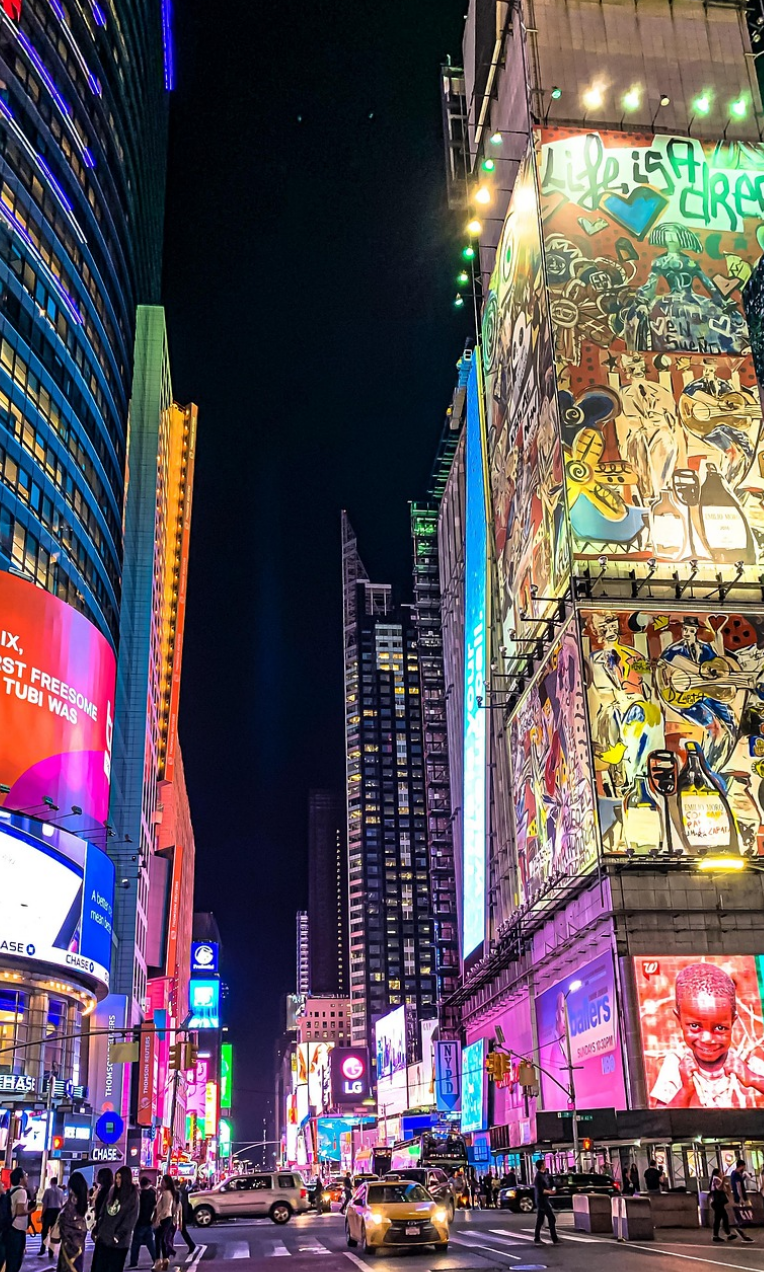 Times Square at night with illuminated billboards, traffic and pedestrians in Midtown Manhattan.